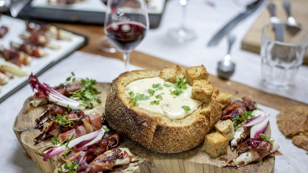 Fondue jambon de Bayonne et fromage de brebis dans une miche de pain au maïs et endives rôties.