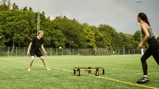 Au spikeball, deux équipes de deux personnes s’affrontent autour d’un mini-trampoline rond, posé à plat au sol. Au spikeball, deux équipes de deux personnes s’affrontent autour d’un mini-trampoline rond, posé à plat au sol.