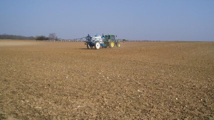 Tracteur avec pulvérisateur dans un champ.