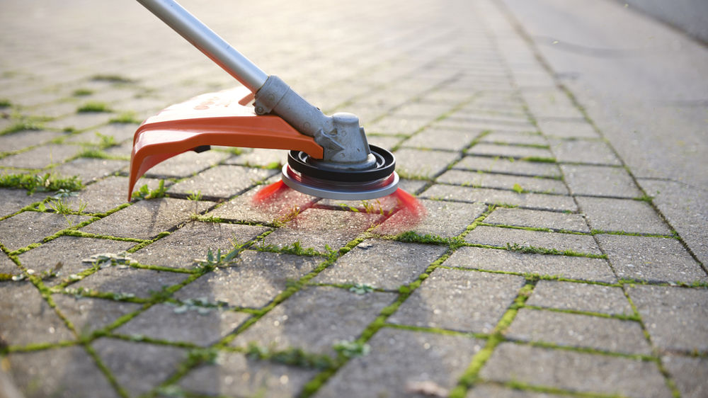 La tête de débroussailleuse universelle « 2 en 1 » peut servir au débroussaillage ou au nettoyage des surfaces dures.