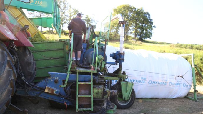 L'ensilage est déversé dans la boudineuse qui compresse le fourrage dans la bâche.